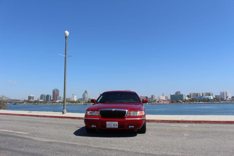 Red 2002 Mercury Grand Marquis with a custom license plate parked by the water