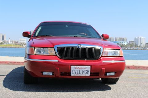 2002 Mercury Grand Marquis - A red 2002 Mercury Grand Marquis is parked by the water, displaying its front grille and California license plate.