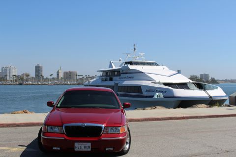 2002 Mercury Grand Marquis - A red 2002 Mercury Grand Marquis is parked in front of a large passenger ferry with a city skyline in the distance.