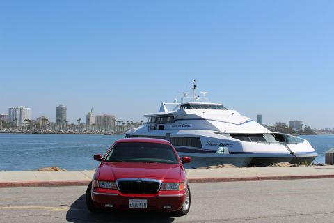 2002 Mercury Grand Marquis - A red 2002 Mercury Grand Marquis is parked near a large passenger ferry with a city skyline in the background.