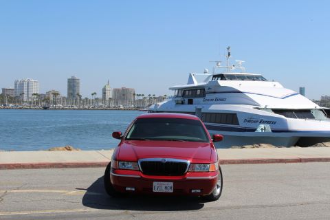 2002 Mercury Grand Marquis - A red 2002 Mercury Grand Marquis is parked in front of a large white ferry with a city skyline in the distance.