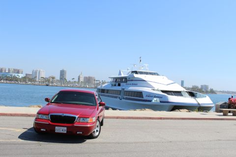 2002 Mercury Grand Marquis - A red 2002 Mercury Grand Marquis is parked near a large passenger ferry with a city skyline in the background.