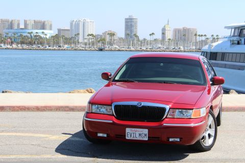 2002 Mercury Grand Marquis - Red 2002 Mercury Grand Marquis parked by the water with a city skyline in the background.