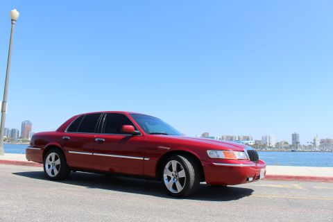 2002 Mercury Grand Marquis - Red 2002 Mercury Grand Marquis parked by the water with a city skyline in the distance.