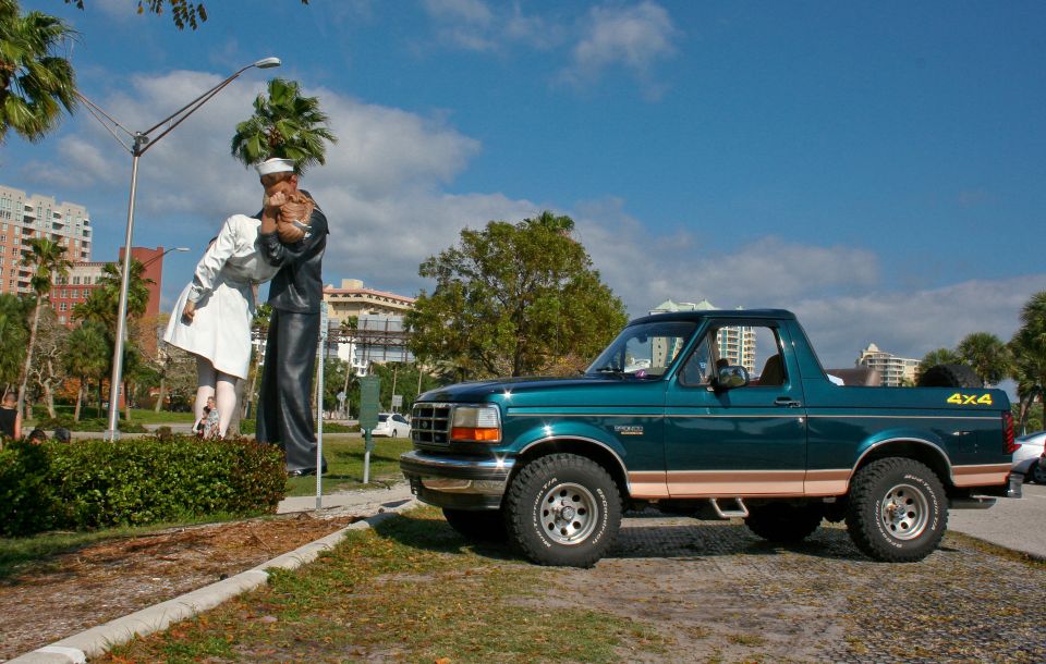 Green 1994 Ford Bronco parked near a statue of a sailor kissing a nurse