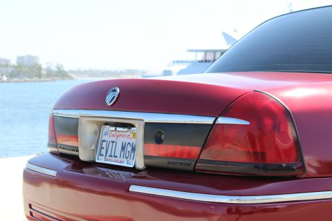 2002 Mercury Grand Marquis - The rear of a red Mercury Grand Marquis is shown parked by the water with a boat in the background.