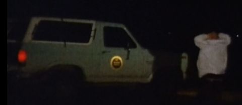1994 Ford Bronco - A white SUV is seen from the side in a dark environment, with a circular emblem on its door.
