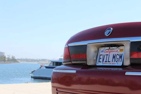 2002 Mercury Grand Marquis - Rear view of a red 2002 Mercury Grand Marquis parked by the water, a custom 'EVIL MGM' California license plate.