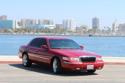 2002 Mercury Grand Marquis - Red 2002 Mercury Grand Marquis parked near a harbor with a city skyline.