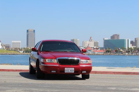 2002 Mercury Grand Marquis - A red 2002 Mercury Grand Marquis is parked in front of a waterfront city skyline.