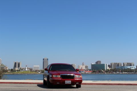 2002 Mercury Grand Marquis - A red 2002 Mercury Grand Marquis is parked with a city skyline in the background.