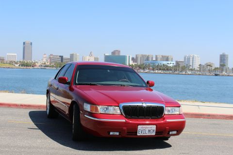 2002 Mercury Grand Marquis - Red 2002 Mercury Grand Marquis sedan parked near a waterfront with a city skyline.