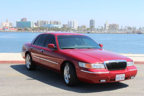 2002 Mercury Grand Marquis - Red 2002 Mercury Grand Marquis with a city skyline and harbor in the background.