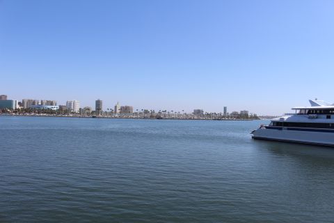 2002 Mercury Grand Marquis - A large white passenger ferry boat is seen sailing on the water with a city skyline in the distance under a clear blue sky.
