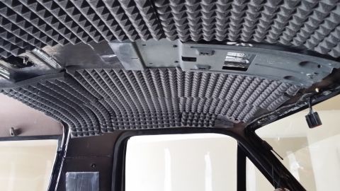 1994 Ford Bronco - The interior ceiling of a vehicle is being fitted with acoustic foam panels for sound dampening.