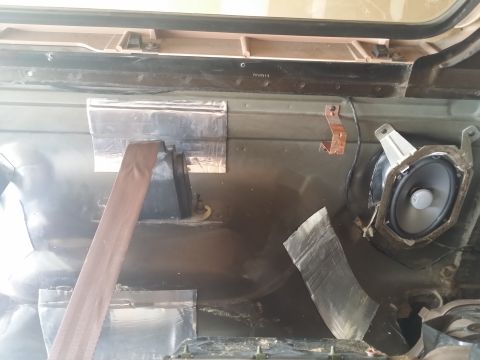1994 Ford Bronco - Interior view of a vehicle door panel with soundproofing material and a removed speaker.