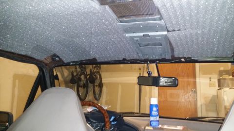 1994 Ford Bronco - Soundproofing material is being applied to the headliner of the vehicle's interior.