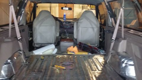 1994 Ford Bronco - The interior of a 1994 Ford Bronco shows soundproofing material being applied to the floor and rear cargo area.