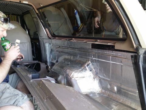 1994 Ford Bronco - A person works on soundproofing the interior of a 1994 Ford Bronco.