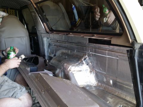 1994 Ford Bronco - Soundproofing material is being applied to the interior door panel of a vehicle.