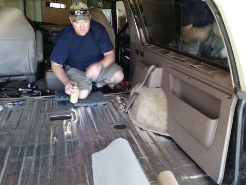 1994 Ford Bronco - A man installs soundproofing material in the cargo area of a 1994 Ford Bronco.