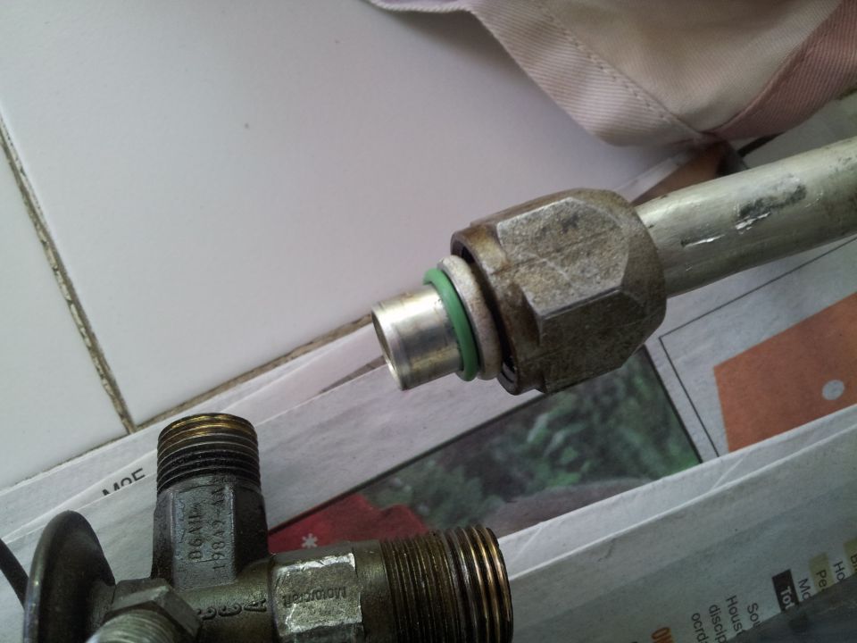 Close-up of an AC hose fitting with a green o-ring. Text on the part reads 'Motorcraft 19849-AA'
