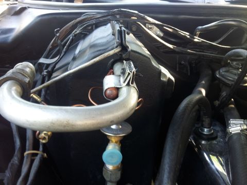 1976 Ford Ranchero - A collection of car parts are displayed on the ground next to a car at an outdoor event.