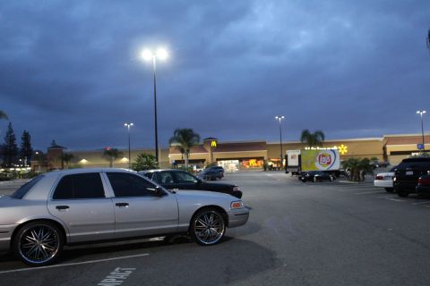 2003 Ford Crown Victoria - silver Ford Crown Victoria sits on chrome spinner wheels in a strip-mall parking lot near a McDonald's at dusk.