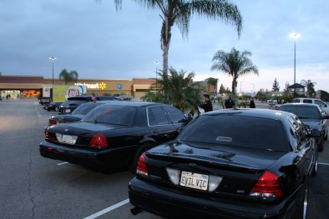 2003 Ford Crown Victoria - Two black Ford sedans, the nearer with an EVIL VIC plate, park in a lot in front of a Walmart store at dusk.