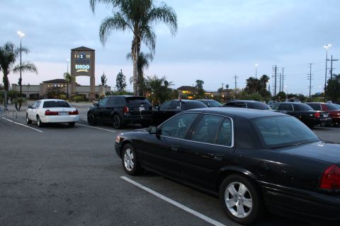 2003 Ford Crown Victoria - black full-size sedan parked in a lot at dusk, with an IHOP and La-Z-Boy storefront sign and palm trees in the background.