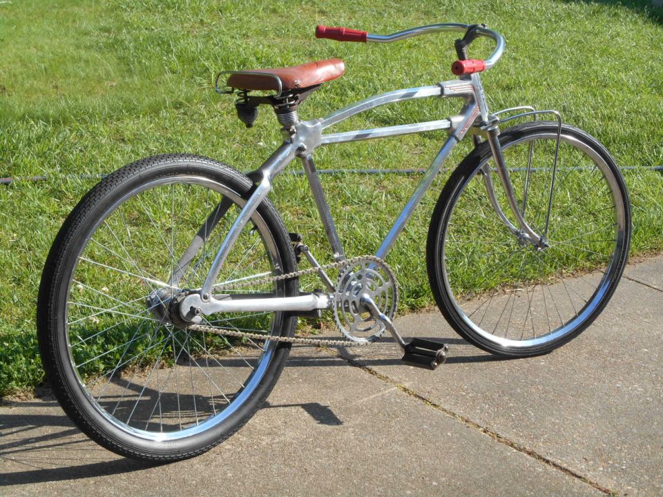 Chrome bicycle with red handlebars and brown seat, side view