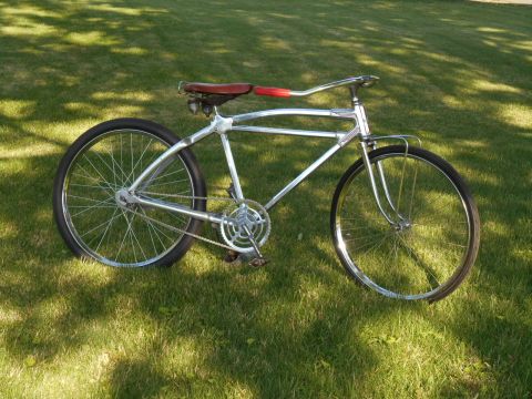 Chrome frame bicycle with red grips and brown leather seat on grass