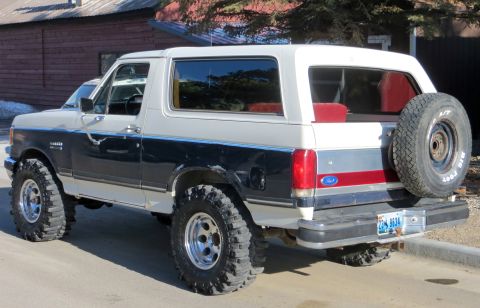 1989 Ford Bronco - This 1989 Ford Bronco is shown from the rear 3/4 angle, a two-tone paint scheme and a spare tire mounted on the tailgate.