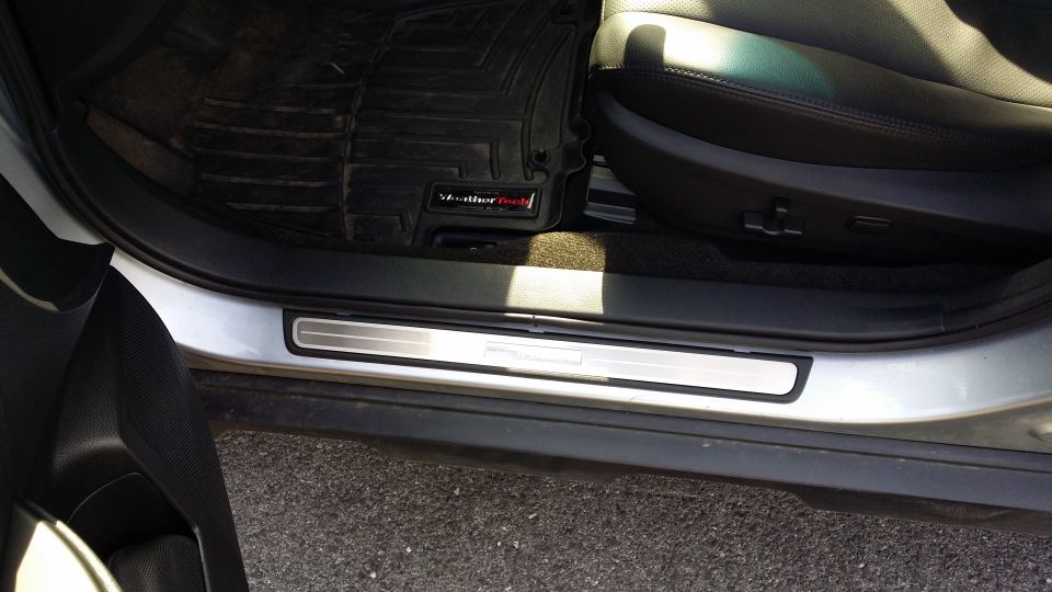 Silver door sill with horizontal lines and a black WeatherTech floor mat inside a car