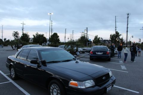 2003 Ford Crown Victoria - black Ford Crown Victoria full-size sedan sits angled in a parking lot at dusk as people gather in the background.