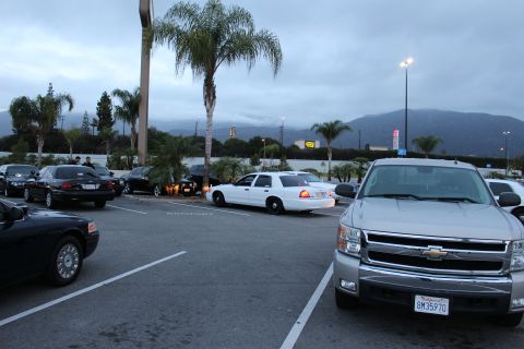 2003 Ford Crown Victoria - silver Chevrolet pickup truck sits beside a white Crown Victoria sedan in a parking lot at dusk with mountains in the distance.