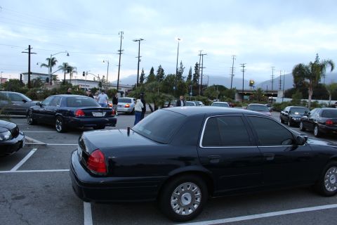 2003 Ford Crown Victoria - dark blue full-size sedan sits angled in a parking lot at dusk with people and other cars in the background.