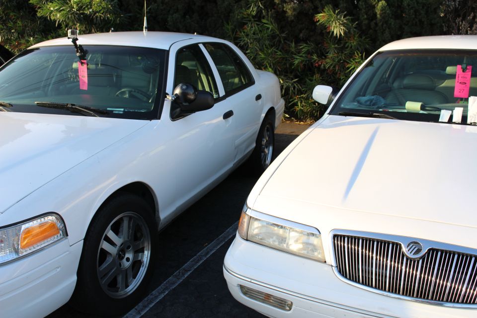 Two white sedans parked side by side, one a Ford and one a Mercury with chrome grille