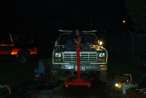 1979 Ford Bronco - A person works on a Ford truck's engine at night, with another truck parked nearby.