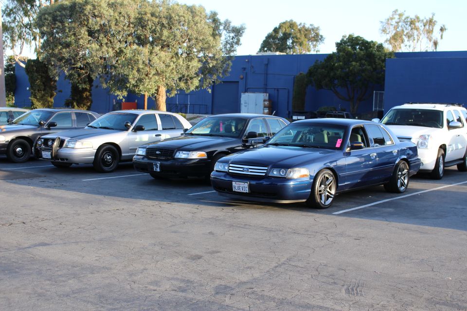 Row of Ford Crown Victoria sedans, black and silver, parked in a lot