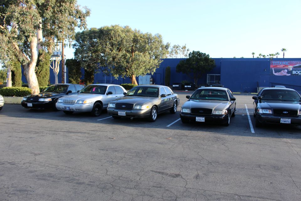 Row of Ford sedans in silver, gold, and black parked by a blue building