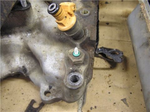 1993 Ford Bronco - A close-up view of a fuel injector attached to an engine manifold, showing mechanical components.
