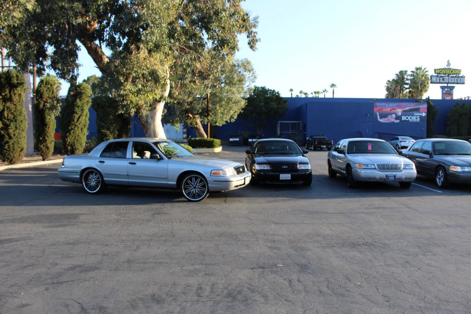 Silver, black, and tan Ford sedans parked by a blue building