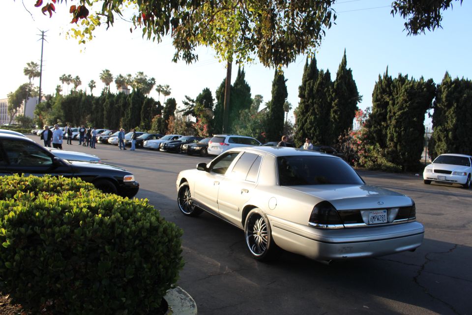 Silver Ford Crown Victoria parked at an angle in a sunlit lot with a plate visible