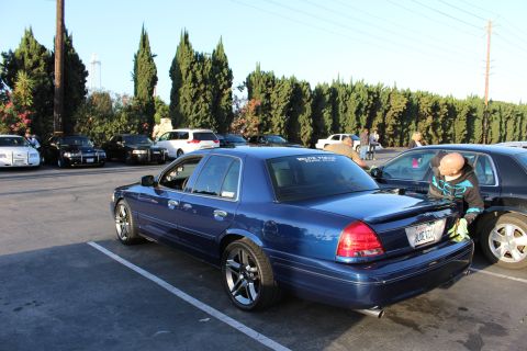 2003 Ford Crown Victoria - lowered dark blue Ford Crown Victoria on chrome wheels parked at a meet, with someone reaching into the car beside it.
