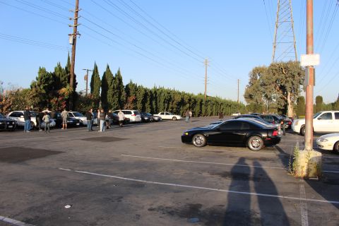 2003 Ford Crown Victoria - black coupe parked in a large asphalt lot, with a row of sedans and a group of people gathered in the background.