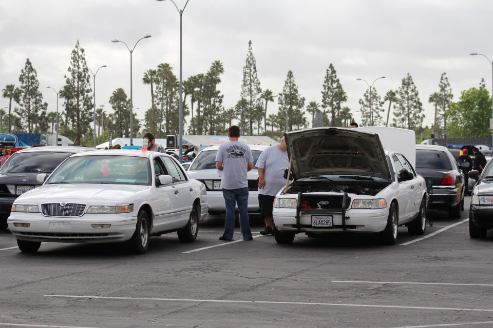 White Lincoln sedan and white Ford with open hood, people nearby