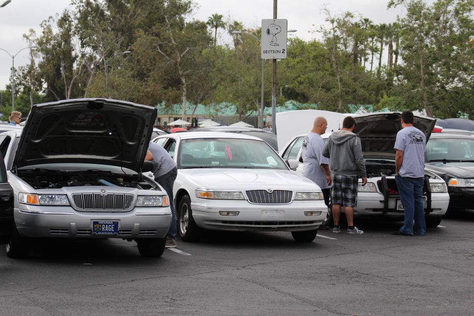 Silver Mercury RAGE and white Lincoln sedans with hoods open, people
