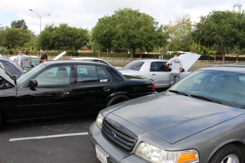 2003 Ford Crown Victoria - gray Ford Crown Victoria shows its front grille and Ford emblem next to black sedans at an outdoor car meet.