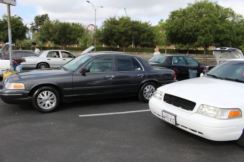 2003 Ford Crown Victoria - dark gray Ford Crown Victoria parks next to a white one wearing a WHTEVIC plate at a parking-lot car meet.